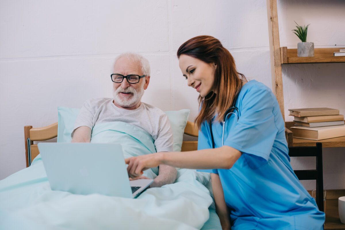 Caregiver reviewing digital medication records with an assisted living resident using a laptop